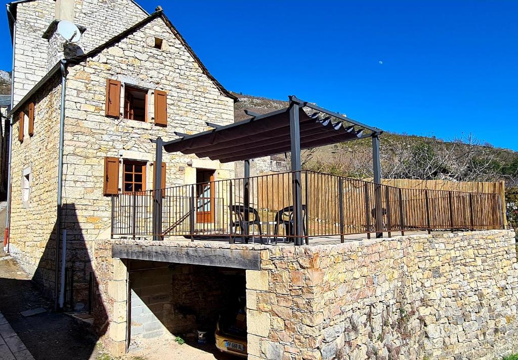 a stone building with a deck on top of it at Gîte la Cardabelle in Ispagnac