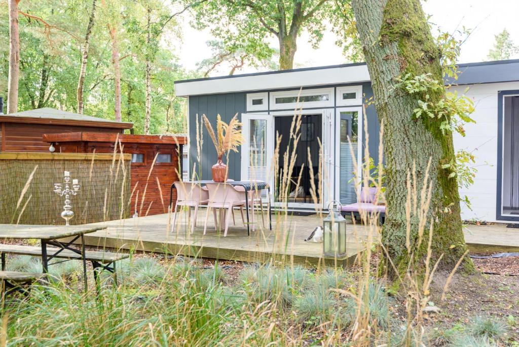 a tiny house in the woods with a table and chairs at Heerlijk Huisje Hoenderloo in Hoenderloo