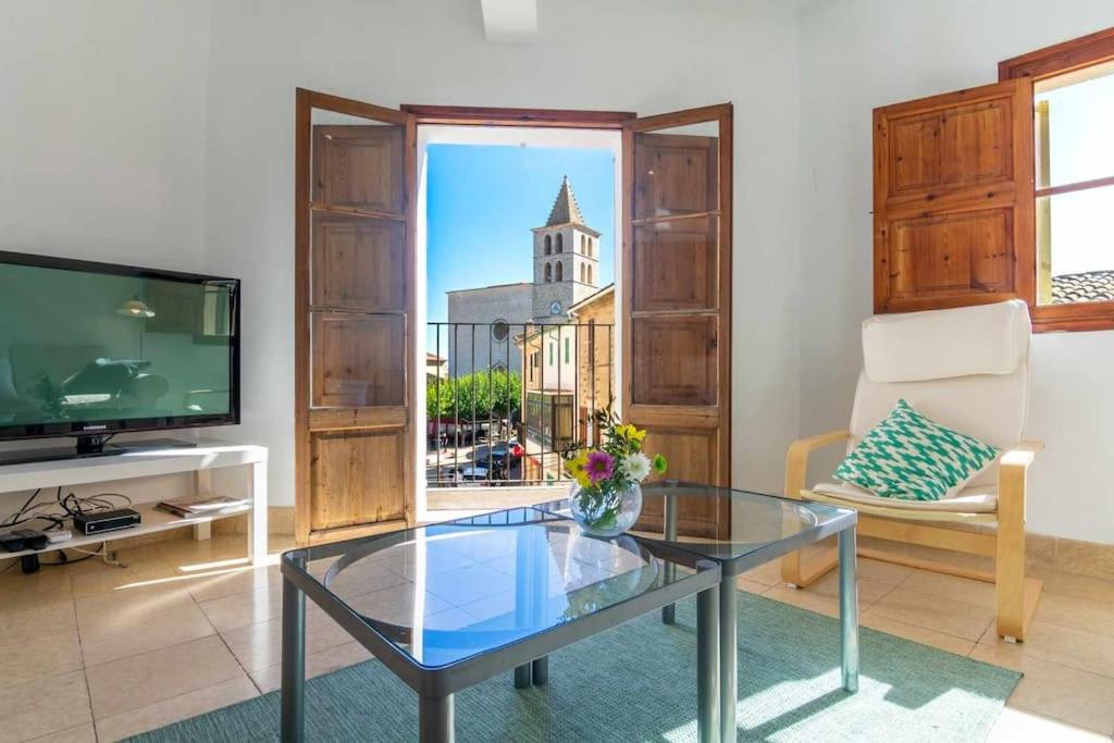 a living room with a glass table and a tv at Maca Sol, adosado con vistas a la montaña in Campanet