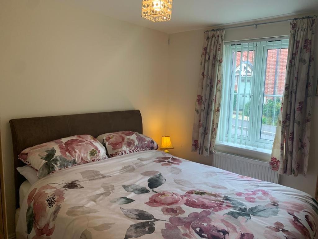a bedroom with a bed with a floral bedspread and a window at Brimsmore Apartment in Yeovil