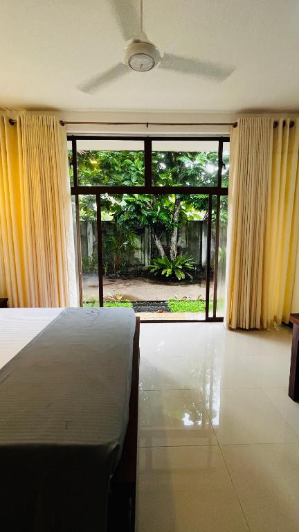 a bedroom with a bed and a large window at New Stay Inn in Bentota
