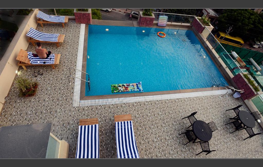an overhead view of a large swimming pool with chairs and a person at Hotel Atulyaa Taj in Agra