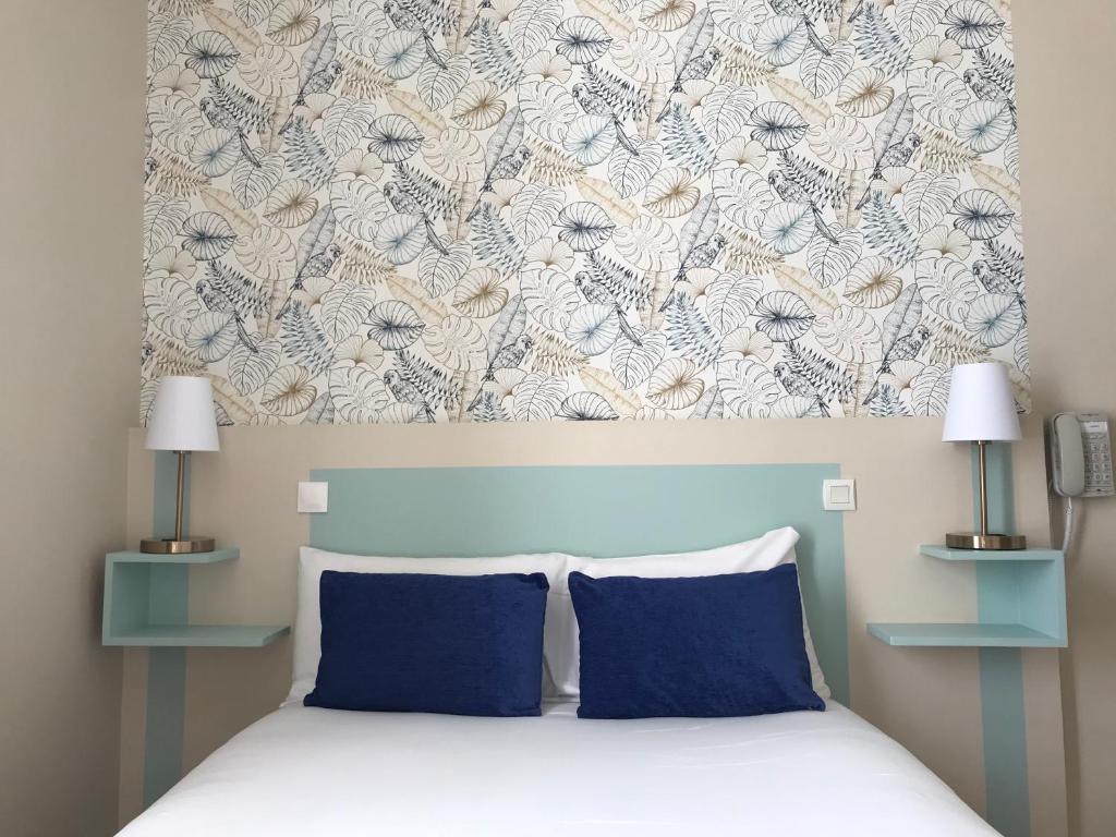 a bed with two blue pillows in a bedroom at Hotel Le Havre Bleu in Beaulieu-sur-Mer