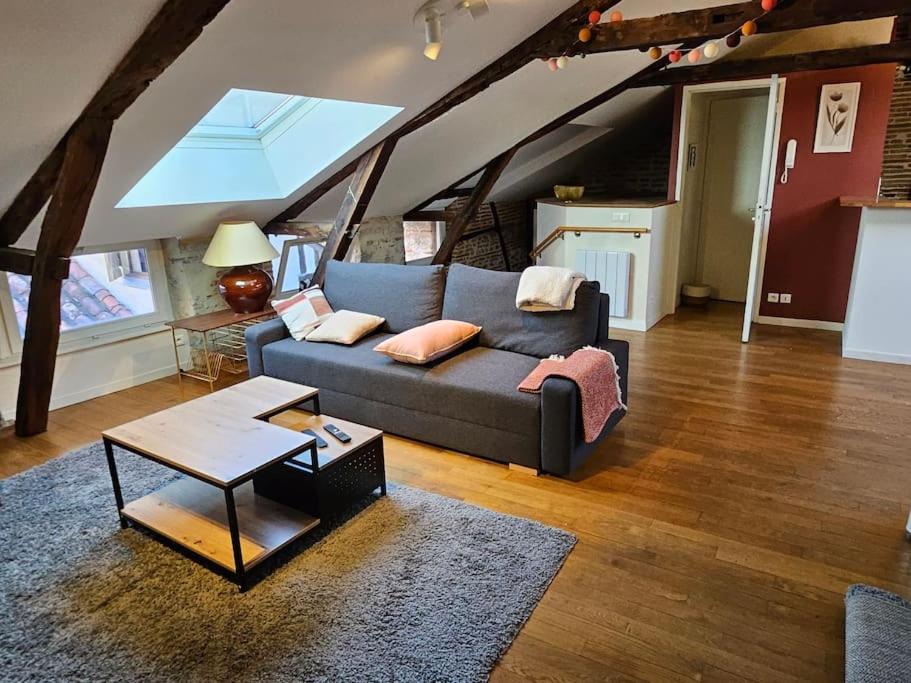 uma sala de estar com um sofá e uma mesa em Sous les toits du vieux Cahors em Cahors