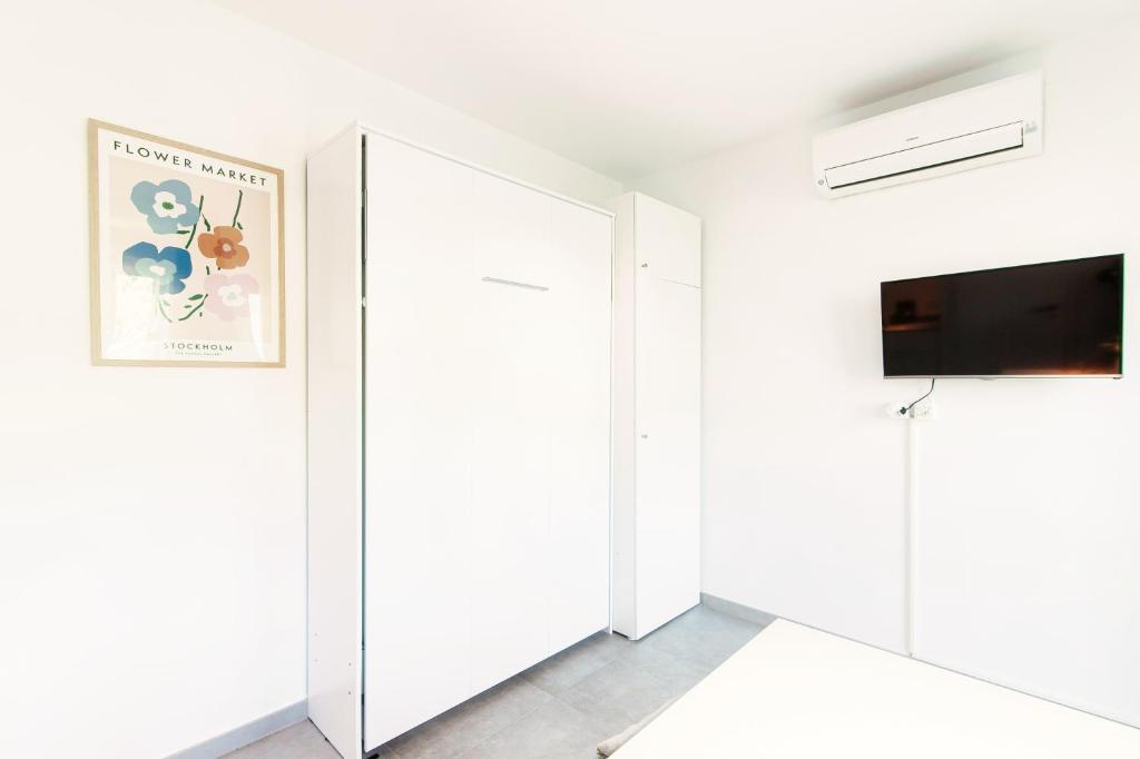 armadio bianco in una camera bianca con TV di Le Betulle Studios by Quokka 360 - studio apartments by the Origlio lake a Origlio