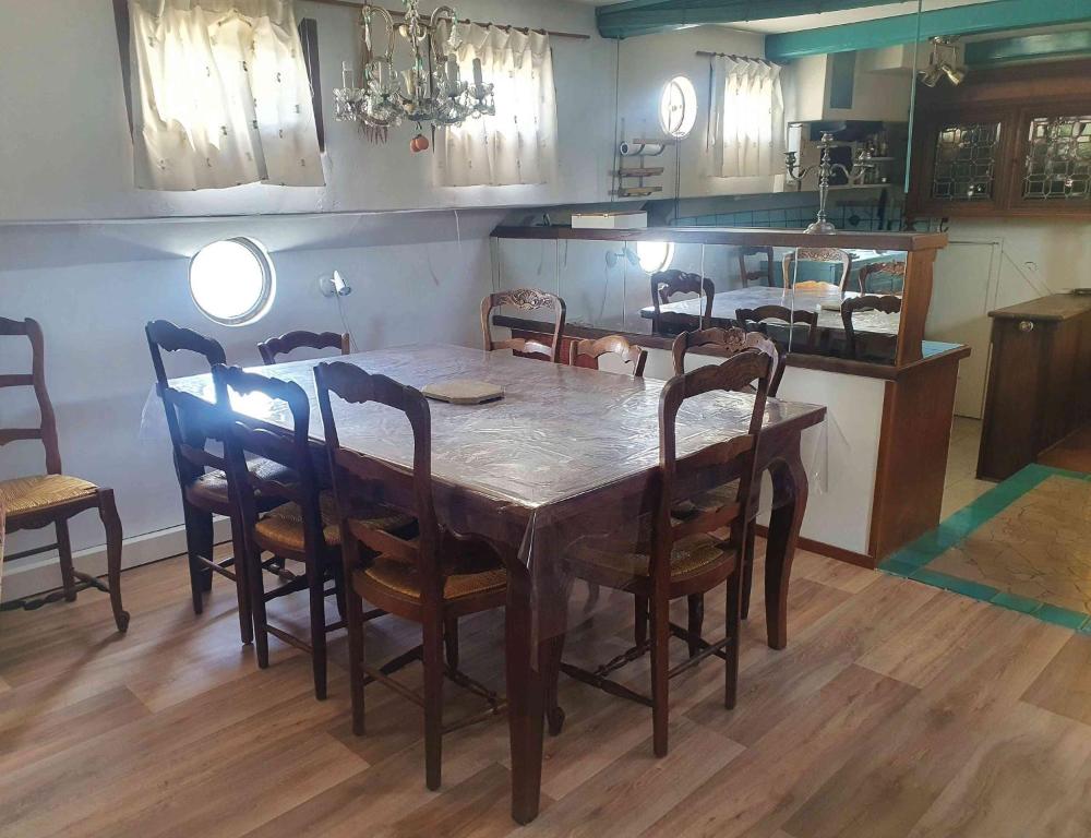 a dining room with a wooden table and chairs at PÉNICHE authentique tout confort in Aigues-Mortes