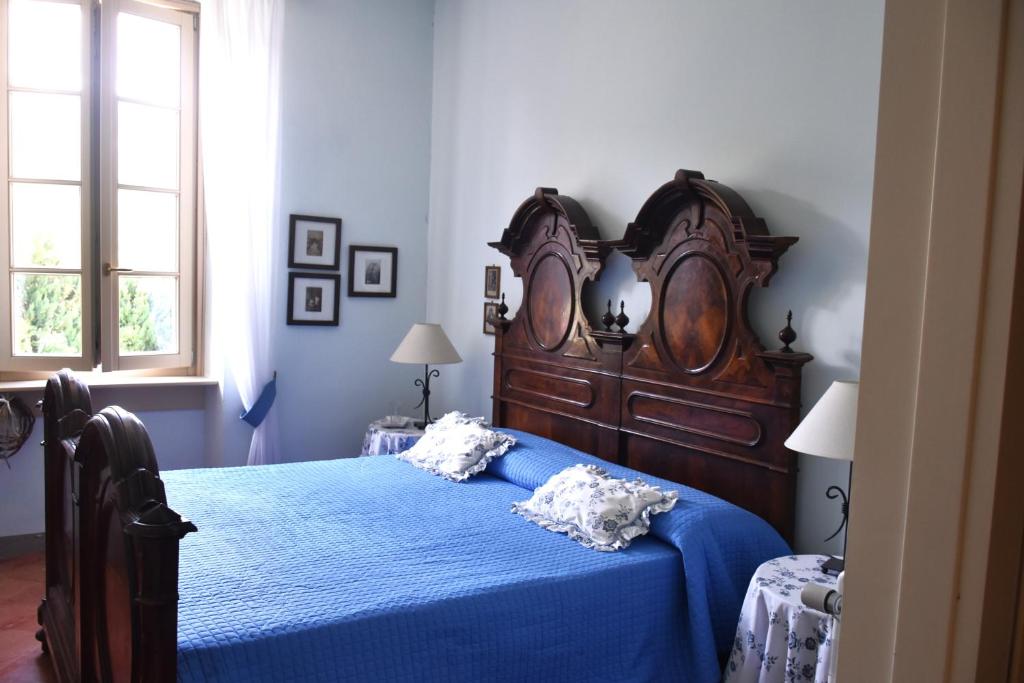 a bedroom with a large wooden bed with blue sheets at Residenza Ca' laRipa in Solto Collina