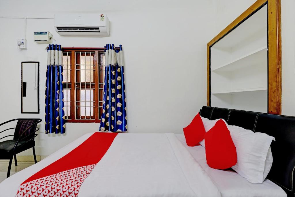um quarto com uma grande cama branca com almofadas vermelhas em OYO K B Residency em Chennai