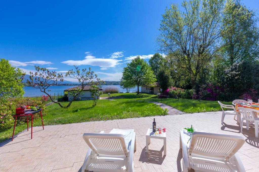 eine Terrasse mit Tischen und Stühlen und Blick auf das Wasser in der Unterkunft Villa Martine Au Bord Du Lac - Happy Rentals in Cadrezzate