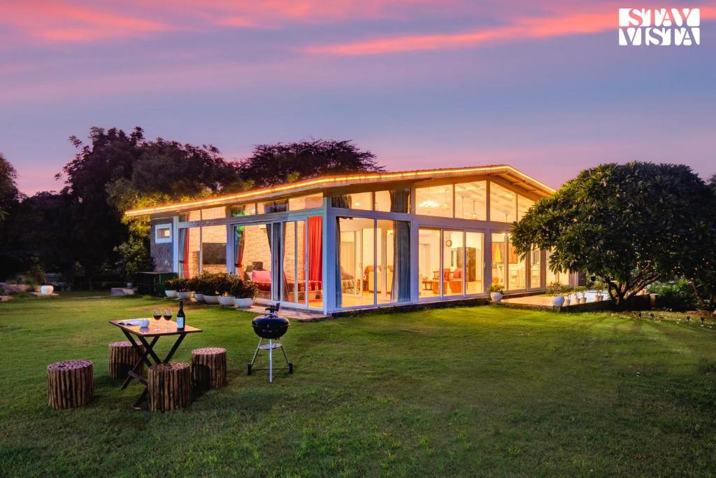 a large glass house with a grill in a yard at StayVista at Idyllic Farmhouse - A Glasshouse with Outdoor Pool in Gurgaon