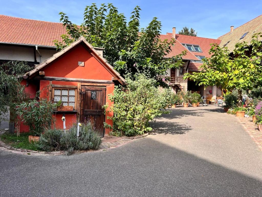 a red house with a driveway in a yard at Appartement dans un corps de ferme alsacien in Mittelhausbergen