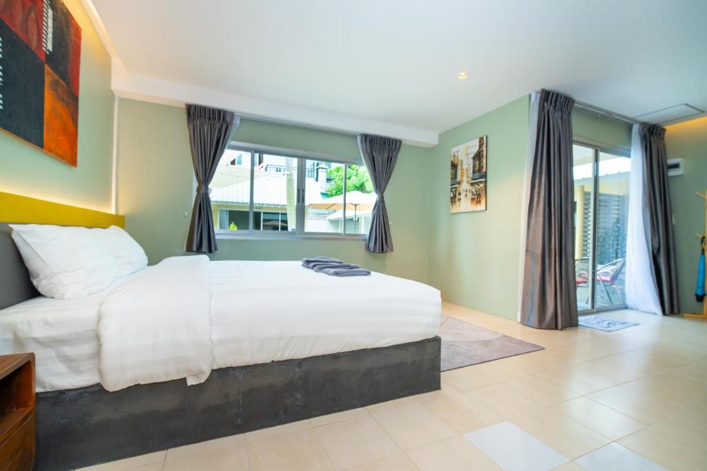 a bedroom with a large white bed and windows at Maiiam Bungalows Kata Beach in Kata Beach