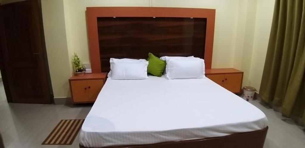a bedroom with a large white bed with green pillows at Drizzle Homestay in Guwahati
