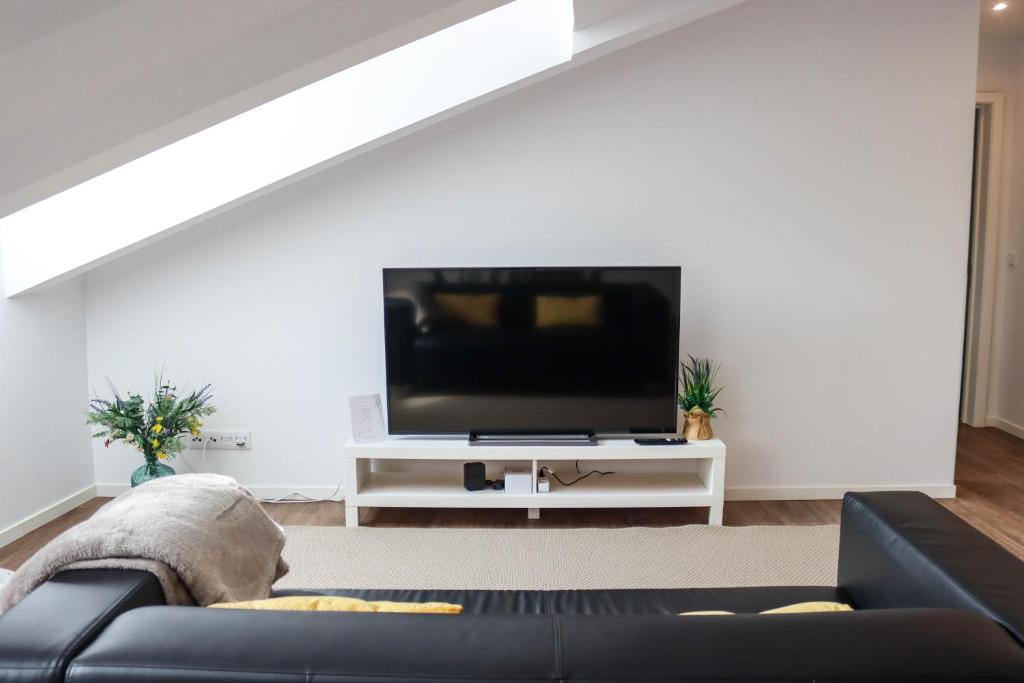 a living room with a black couch and a flat screen tv at São Miguel Charming House by LFC Apts in Ponta Delgada