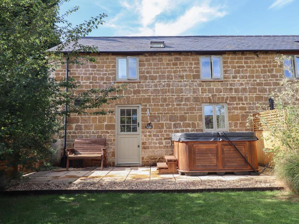 a brick house with a hot tub in the yard at The Stables in Chipping Norton