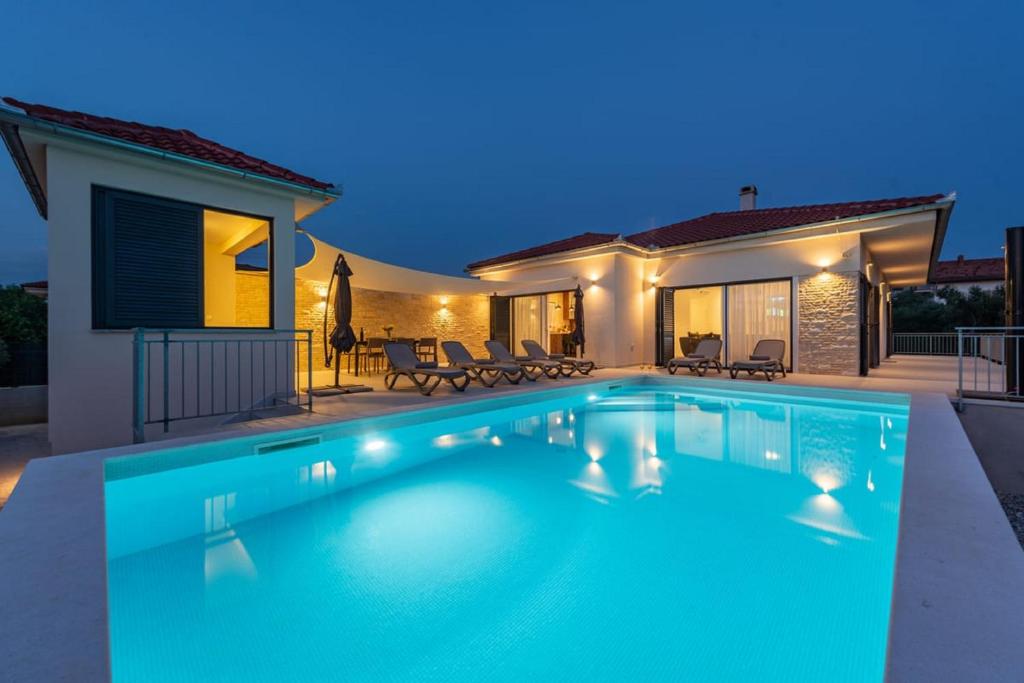 a swimming pool in front of a house at Villa Paloma with pool in Sukošan