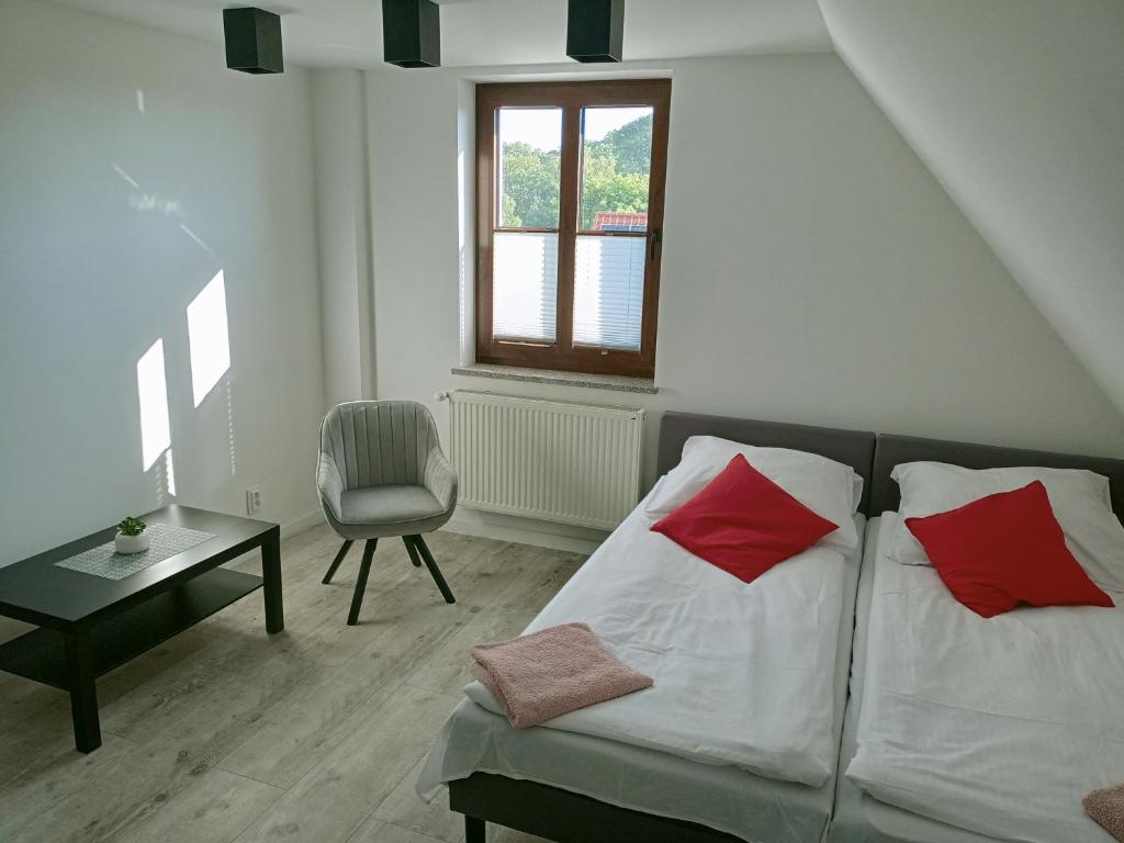 una camera da letto con un letto con cuscini rossi e una sedia di Apartamenty przy zamku a Pasłęk