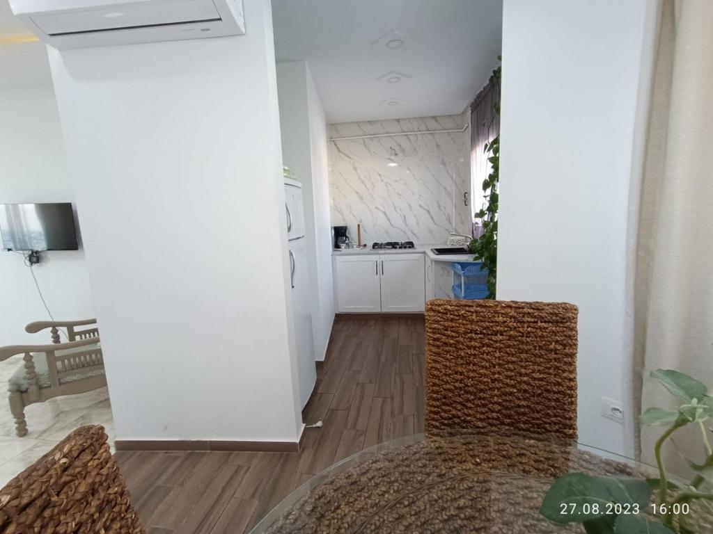 a kitchen with white walls and wooden floors and chairs at TIM Haute standing appartment S2, center Monastir in Monastir