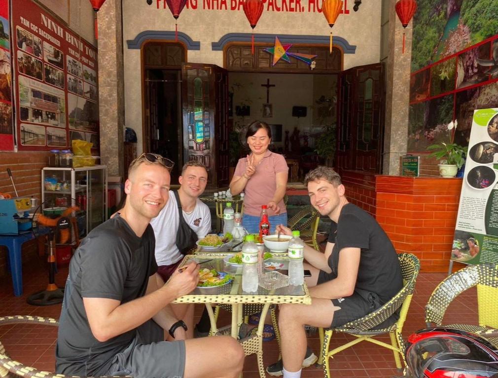 grupa ludzi siedzących przy stole jedzących jedzenie w obiekcie Phong Nha Backpacker Hostel w mieście Cừ Lạc