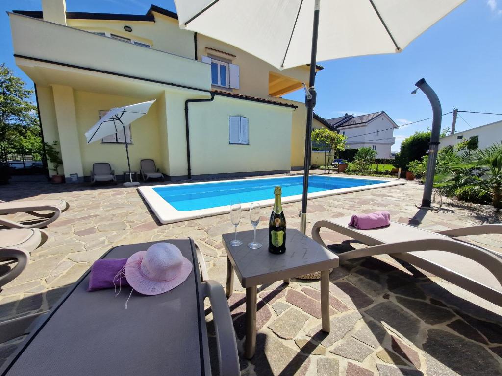 a villa with a pool and a table with a bottle of wine at House Vertel in Matulji