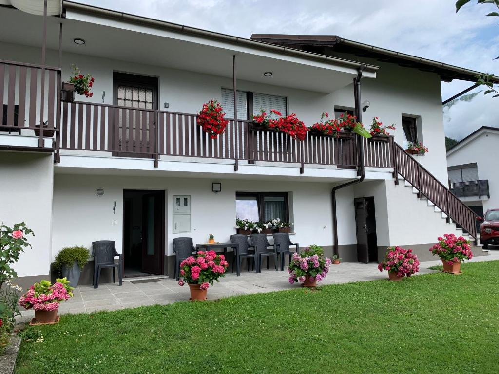 une maison blanche avec des fleurs sur le balcon dans l'établissement APARTMA PANORAMA, à Kobarid