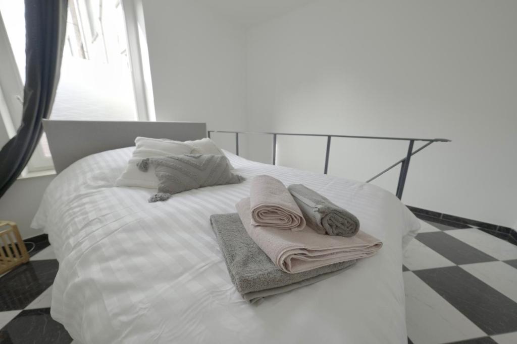 Una cama blanca con toallas y almohadas. en Studio Didine, en Charleroi