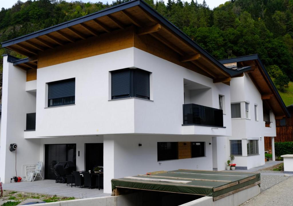 a white house with black shuttered windows at Apart Christoph in Oetz