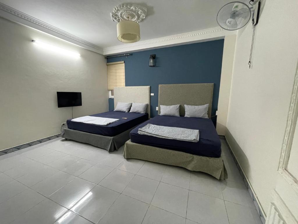 two beds in a room with blue walls and white floors at Sword lake hostel in Hanoi