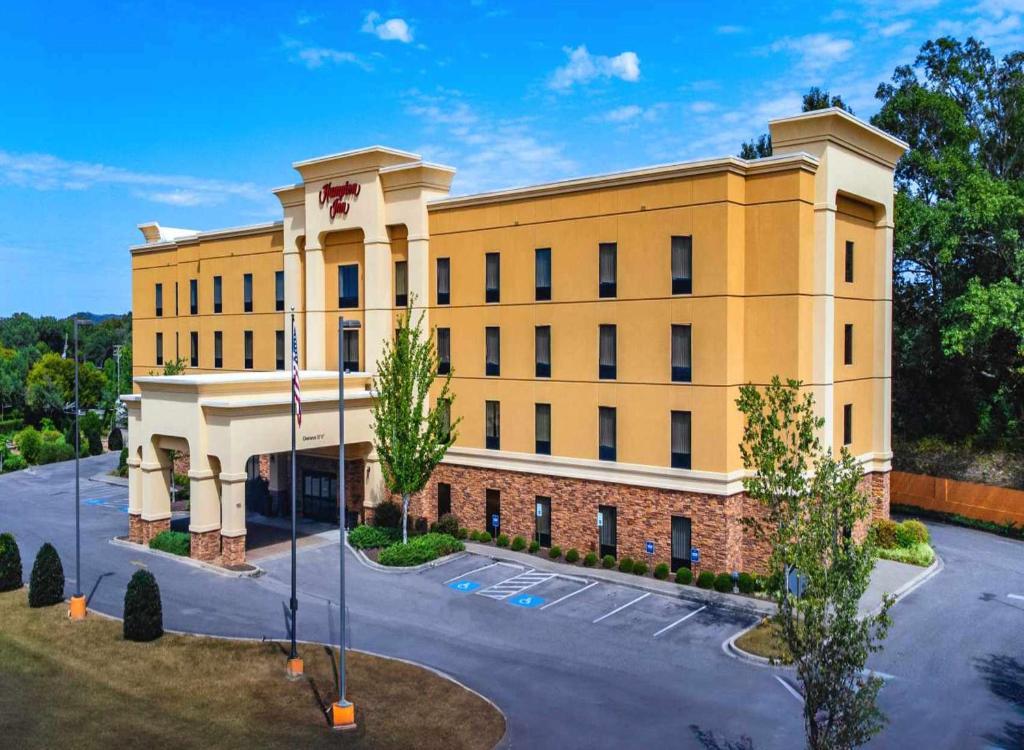 un gran edificio amarillo en un estacionamiento en Hampton Inn Fayetteville, en Fayetteville