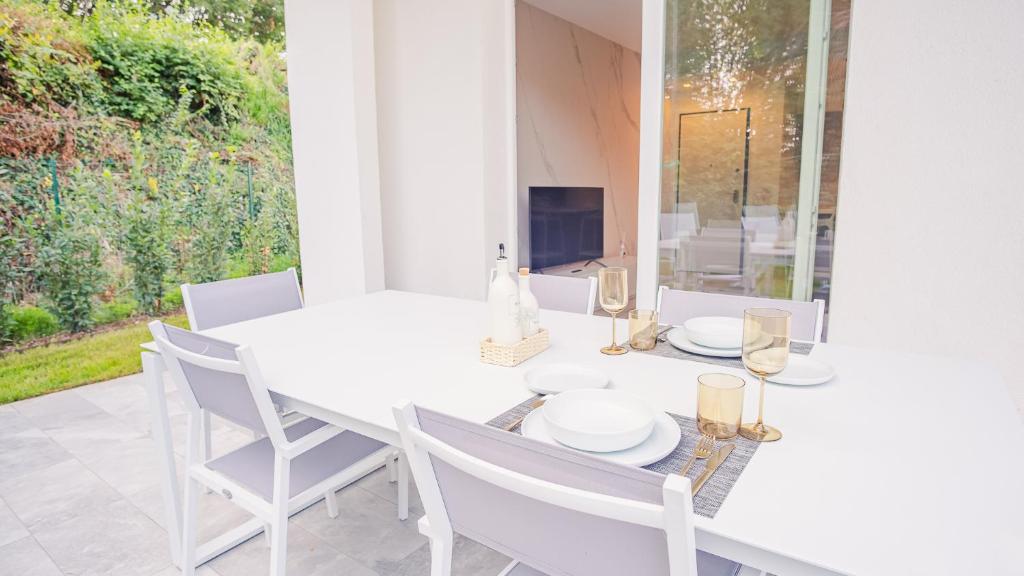 Un comedor blanco con una mesa y sillas blancas. en Garda Luxury Suite - Italian Homing, en Padenghe sul Garda