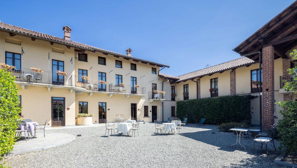 un patio con mesas y sillas frente a un edificio en Best Western Plus Hotel Le Rondini, en San Francesco al Campo