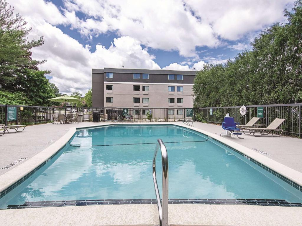 a swimming pool with chairs and a building in the background at La Quinta by Wyndham Portland in Portland