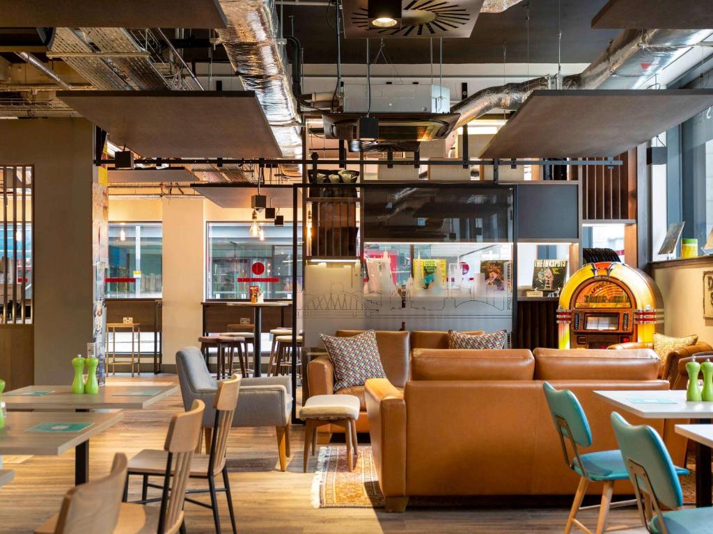un restaurante con sofás, mesas y sillas en ibis Styles Glasgow Central, en Glasgow