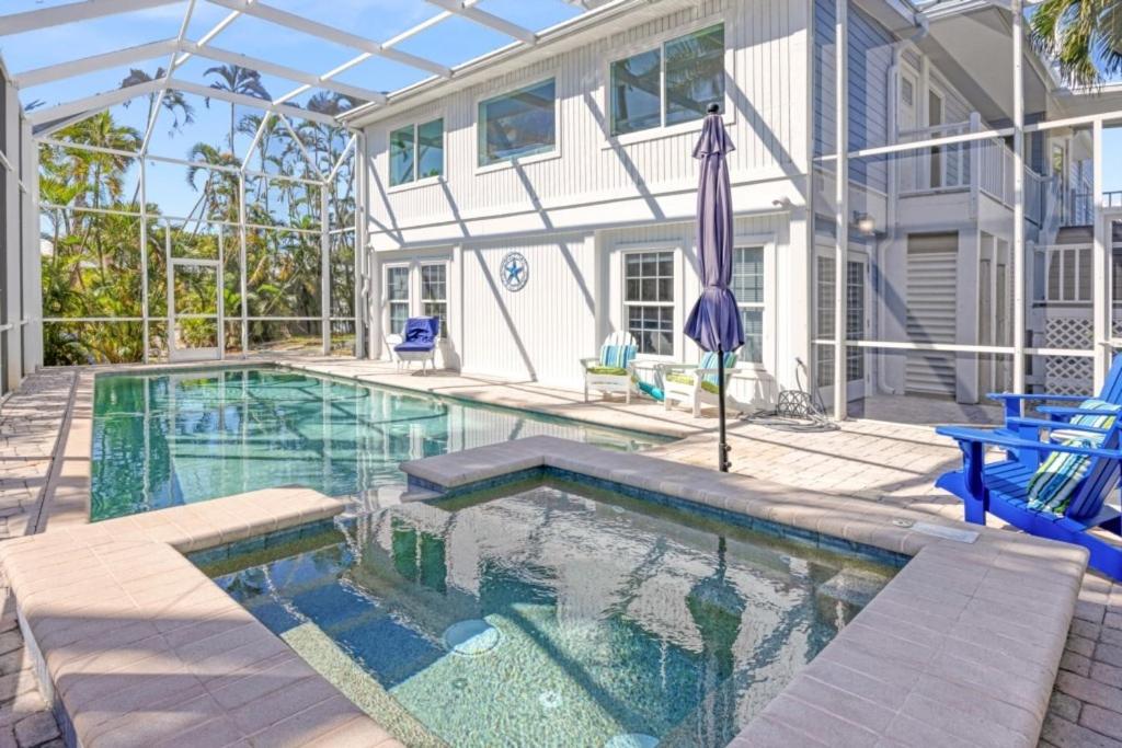 a swimming pool with an umbrella and a house at Murmond- Captiva Home in Captiva