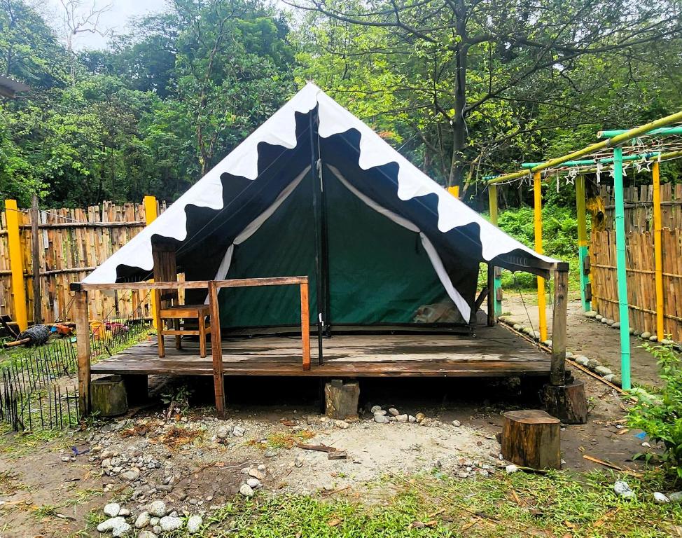 a tent with a chair on a wooden platform at Beyond Brahmaputra Campsite 