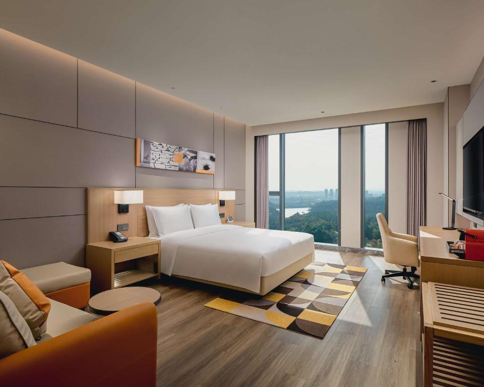 成都市にあるHyatt Place Chengdu Bio-Townのベッド、デスク、ソファが備わるホテルルームです。