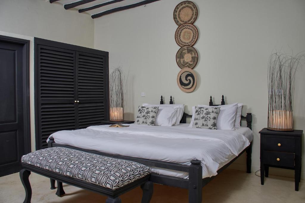 a bedroom with a large white bed with a bench at Saffron Garden Malindi in Malindi