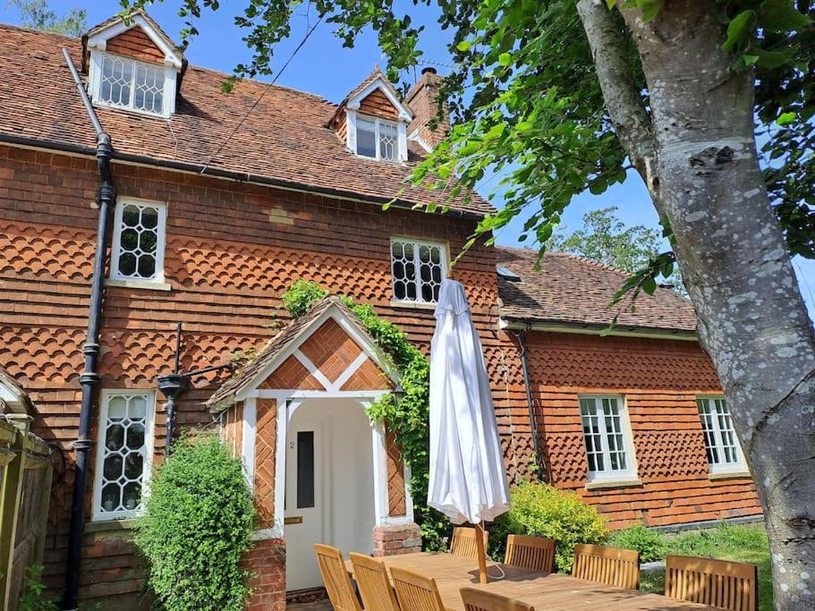 uma casa com um guarda-sol, uma mesa e cadeiras em Cottage 2, Northbrook Park, Farnham-up to 6 adults em Farnham