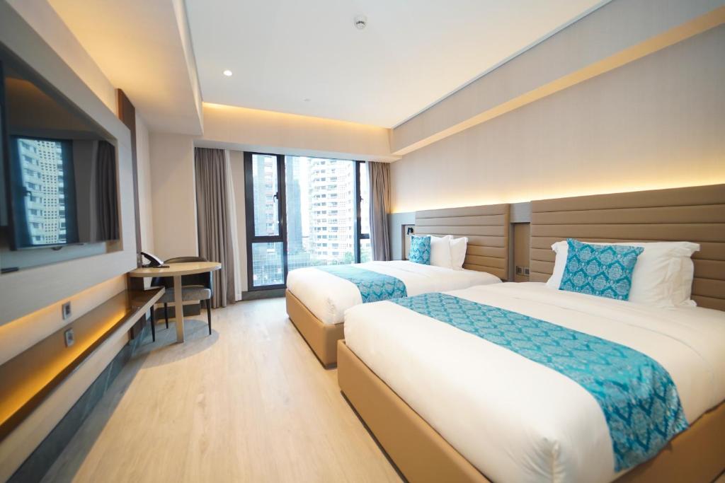 Habitación de hotel con 2 camas y TV de pantalla plana. en Bayprime Hotel, en Manila