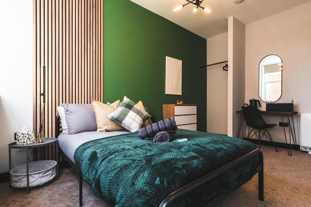 ein Schlafzimmer mit einem Bett mit einer grünen Wand in der Unterkunft Dreamy Derby City Apartment Free Wi-Fi & Parking in Derby