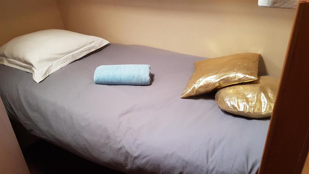 a bed with two pillows and a blue towel on it at PÉNICHE authentique tout confort in Aigues-Mortes