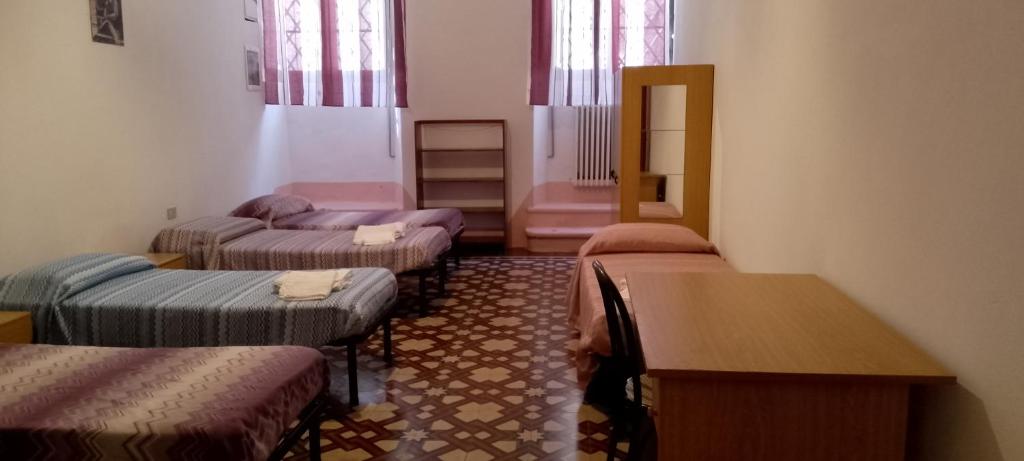 een kamer met vier bedden en een tafel erin bij L'Oasi - Locazione Turistica Pisa in Pisa