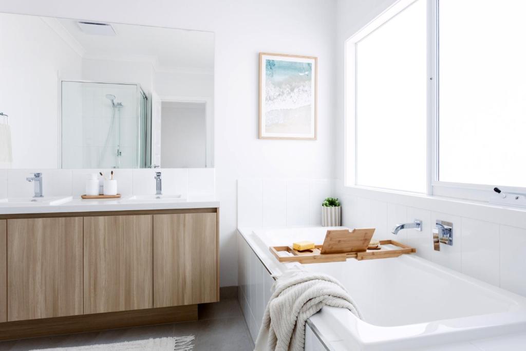 a white bathroom with a tub and a sink and a bath tub at Rosebay - Coastal Holiday Home in Rosebud