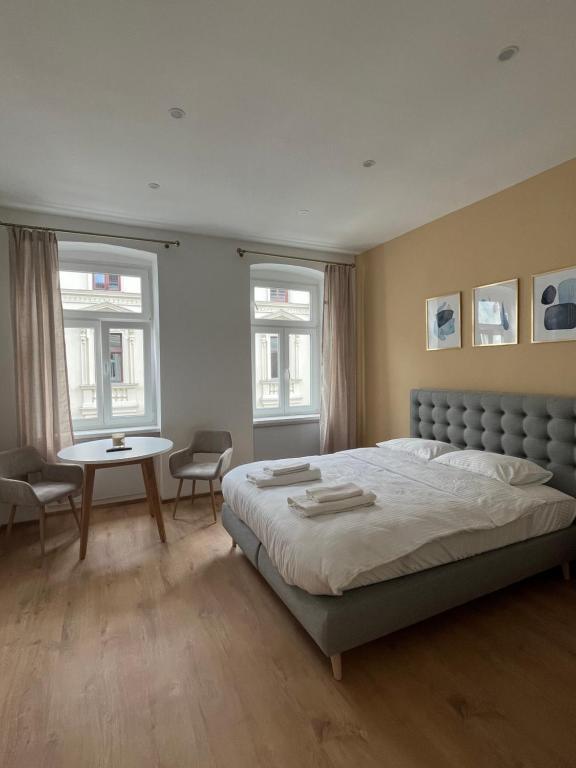 ein Schlafzimmer mit einem Bett, einem Tisch und zwei Fenstern in der Unterkunft Apartment 19 near Metro & Netflix in Wien