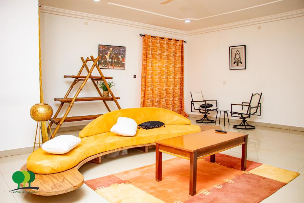salon z żółtą kanapą i stołem w obiekcie VILLA DE L'INTEGRATION w mieście Wagadugu
