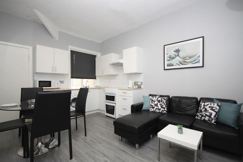 a living room with a couch and a table and a kitchen at Central Beach Apartment & Free Parking in Blackpool