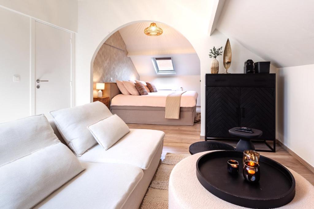 a living room with a white couch and a bed at B&B Maison La Belle in Zoutleeuw