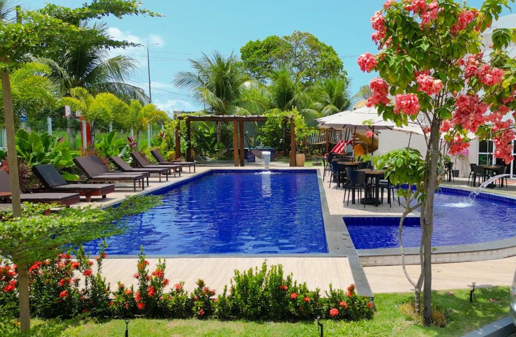 una piscina en un complejo con sillas y flores en Altiplano Hotel, en João Pessoa