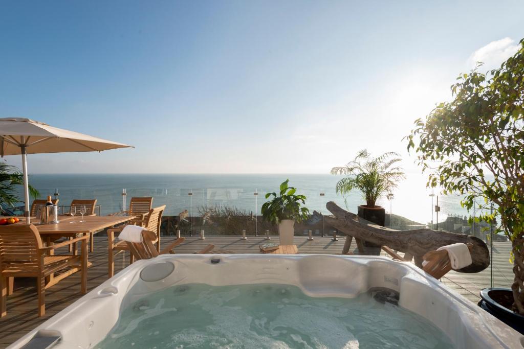 a jacuzzi tub on a patio with a view of the ocean at Big Luxury House sleeps 12/14. Sea Views, Hot tub. in Hollington