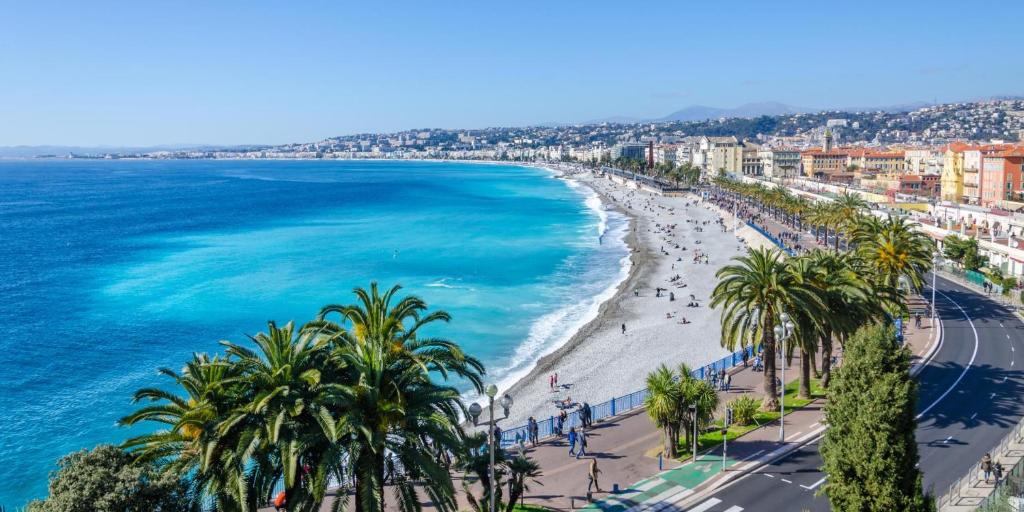 a view of a beach with palm trees and the ocean at Voilier Love Menton in Menton
